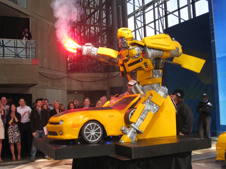 there is a big yellow robot standing next to a small car