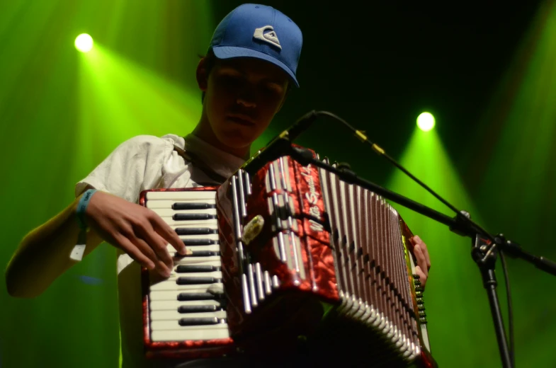 a young man holding an accordion while standing next to a microphone