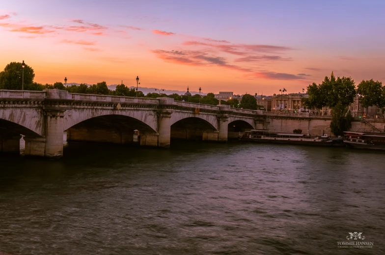 sunset over river with old bridge and cars passing by