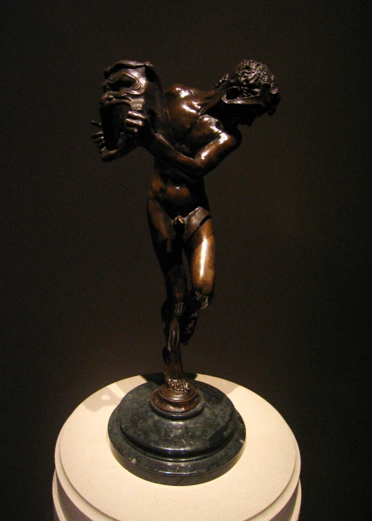 a bronze figurine is holding a snake on top of a round object