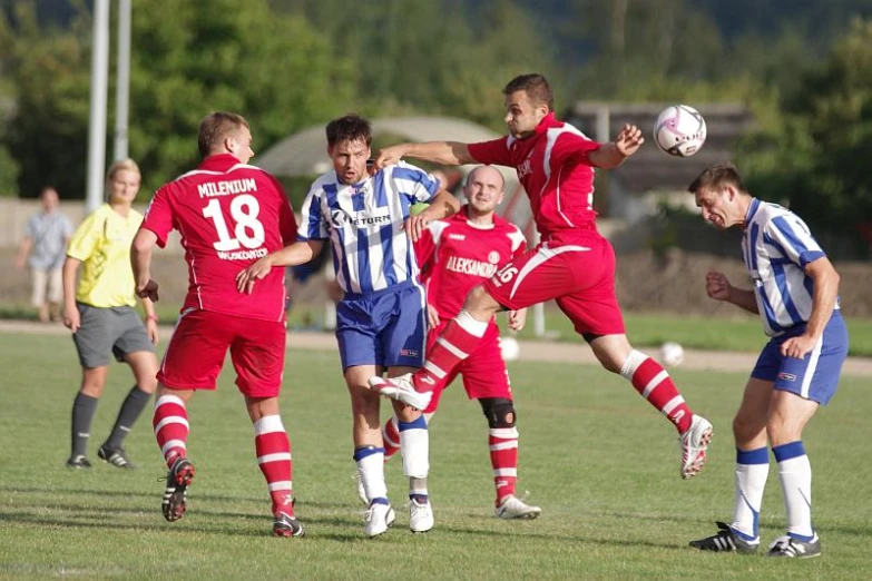 people in red and blue uniforms on a field playing soccer