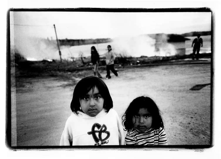 two children stand in front of a fire as it burns