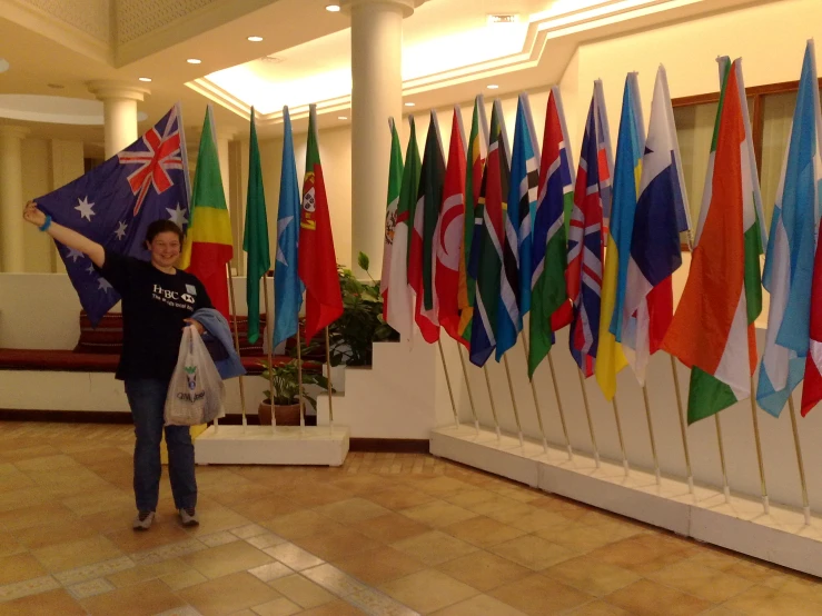 woman with hand up holding several flags and two flags with flags painted on them