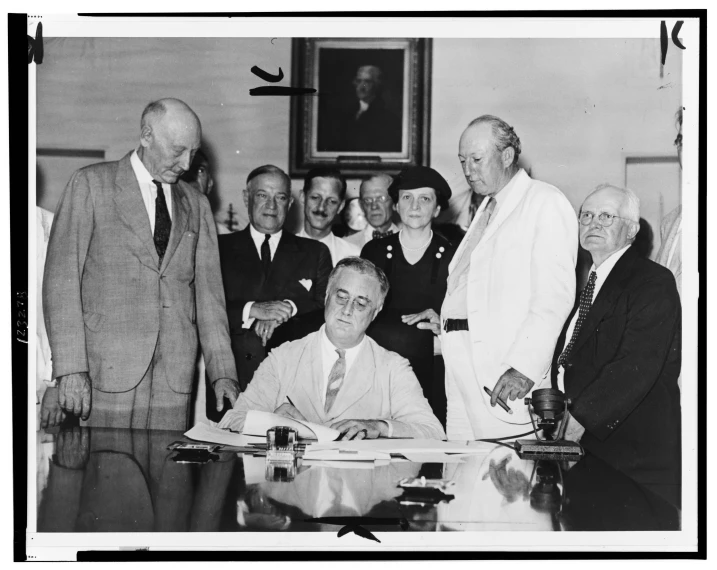 an old black and white po shows a group of people standing around a man signing