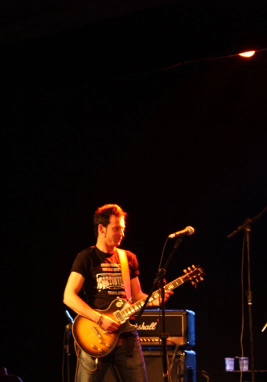 a male in a black shirt playing guitar