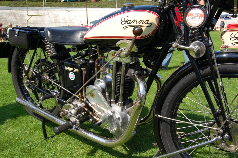 a motorcycle is parked on some grass and some people