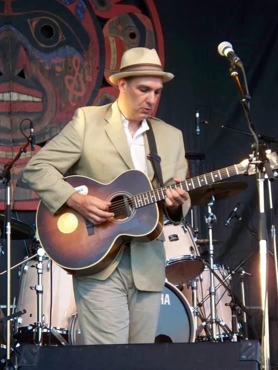 man in a gray suit playing guitar at the stage