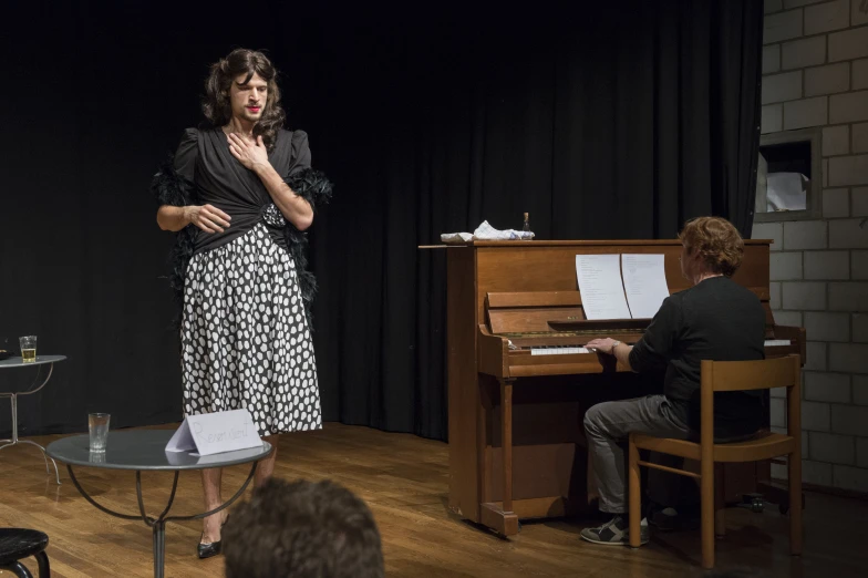 a woman standing in front of a piano with her hands near her face