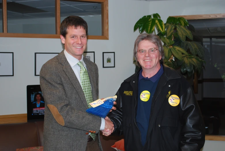 two men shaking hands in front of a tree