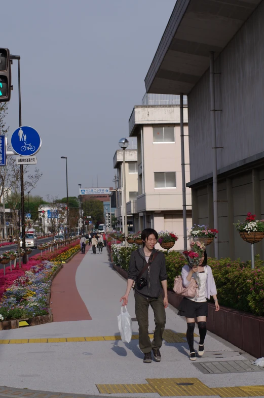 two people are walking down the street near a stoplight