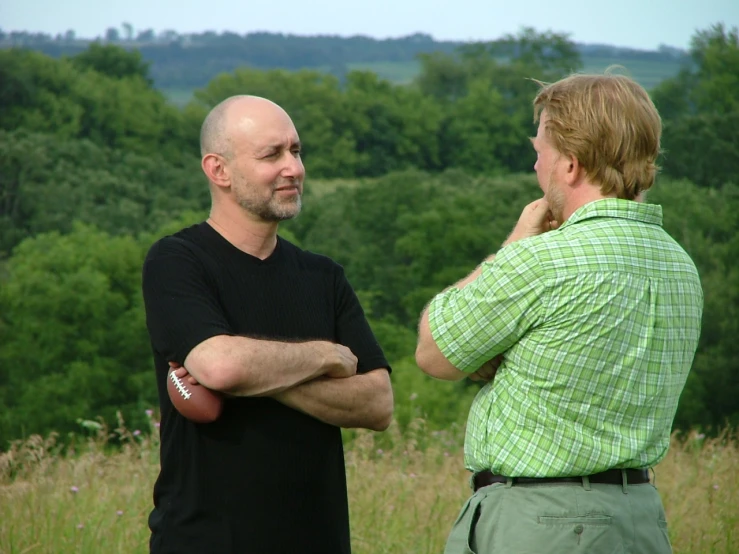 a man in black shirt and a man with green shirt standing in grass