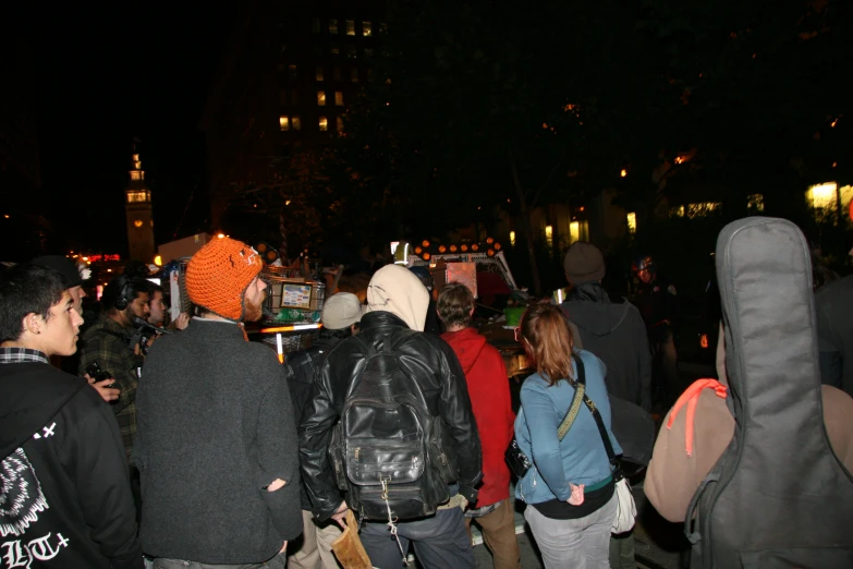 a crowd of people standing around a street with a light on