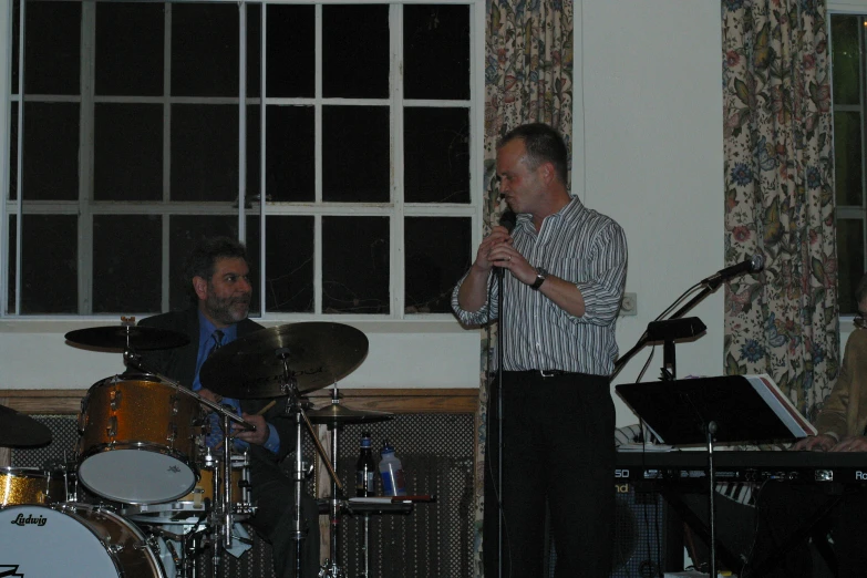 a man stands in front of a band on stage