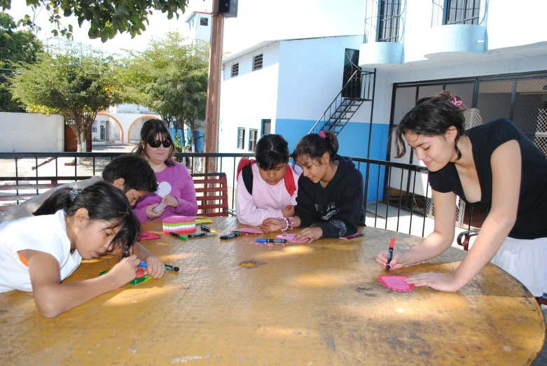 a group of girls sitting around a wooden table