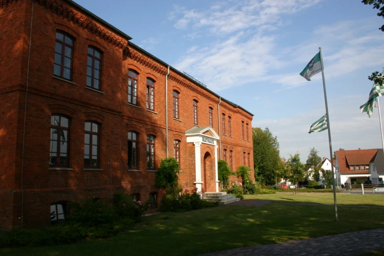 a building with some flags on the lawn next to a flag pole