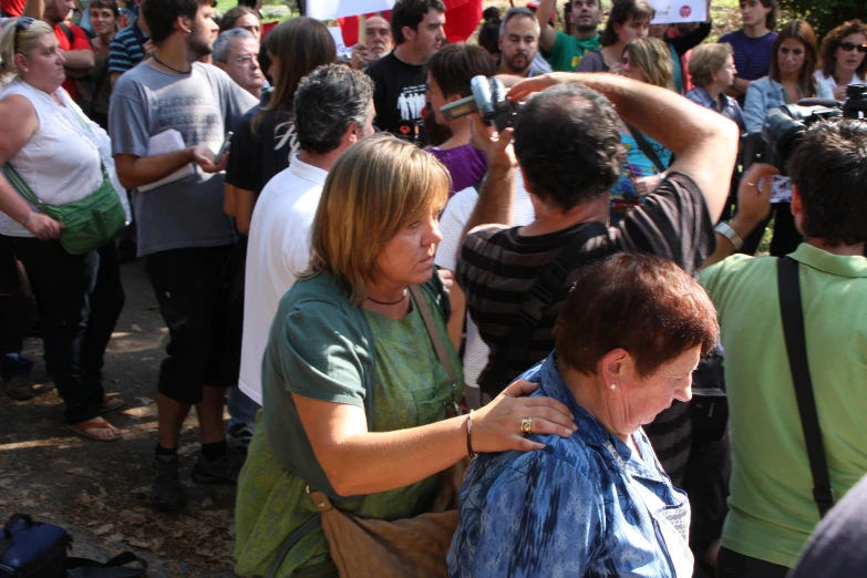 a woman combs another women's hair while others look on