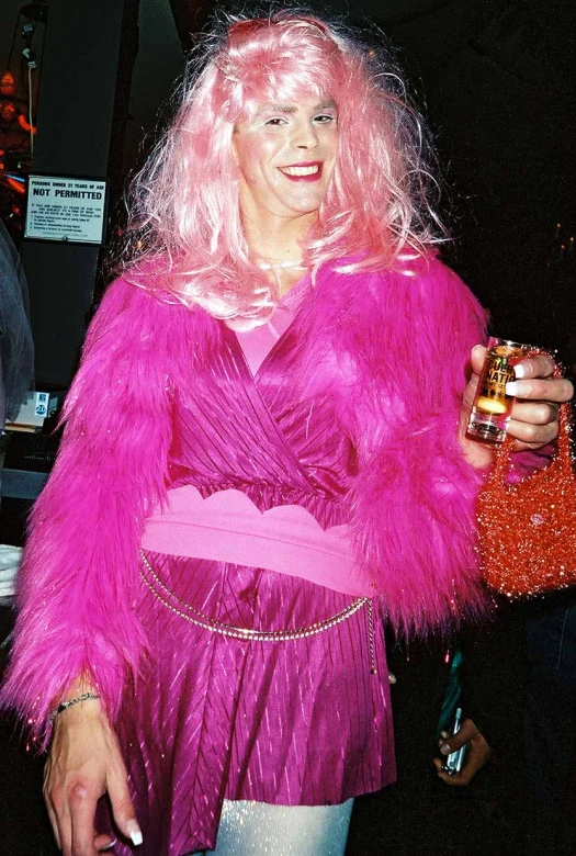 a woman in pink and pink fur jacket holding a orange purse