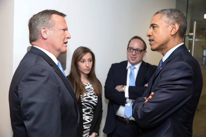 two men talk to a group of young women in suits