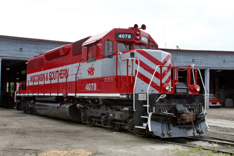 a red train is traveling down the tracks in front of a building