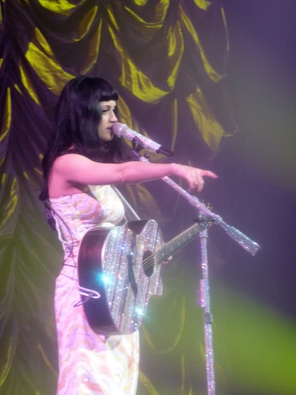 an asian woman with a microphone and guitar on stage