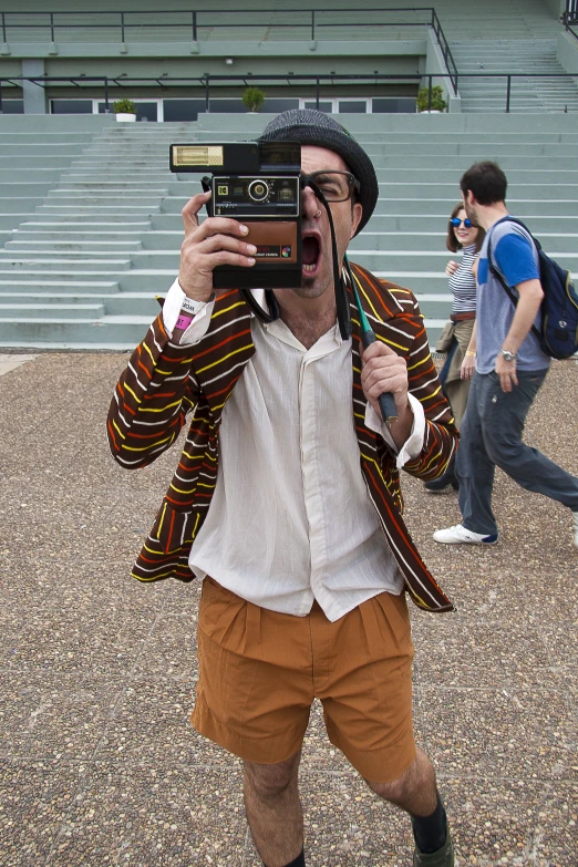 a man with glasses and a cardigan jacket holding a camera