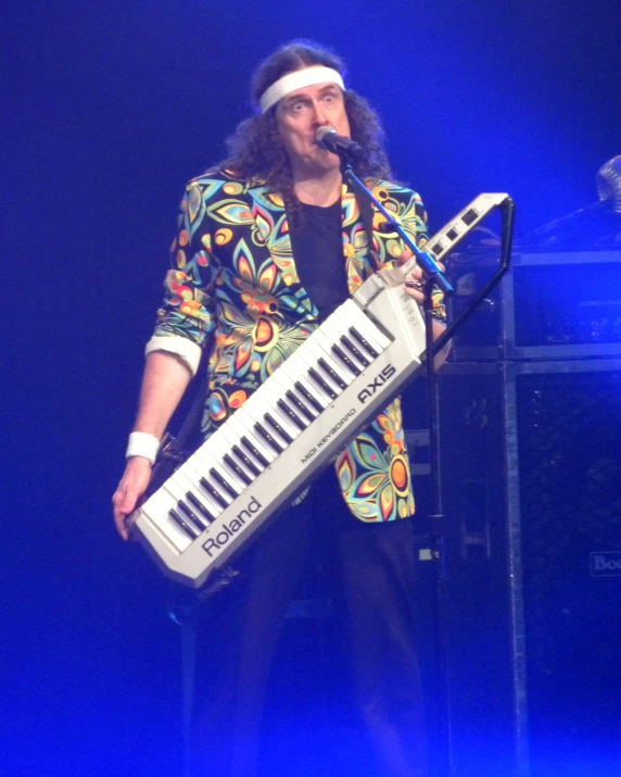 a man playing an electronic keyboard in front of a microphone