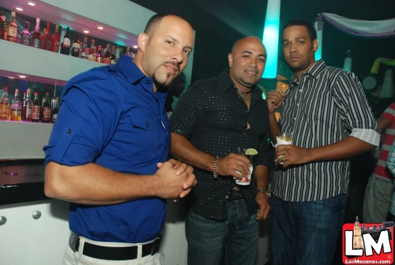 three men standing around drinking beverages at a bar