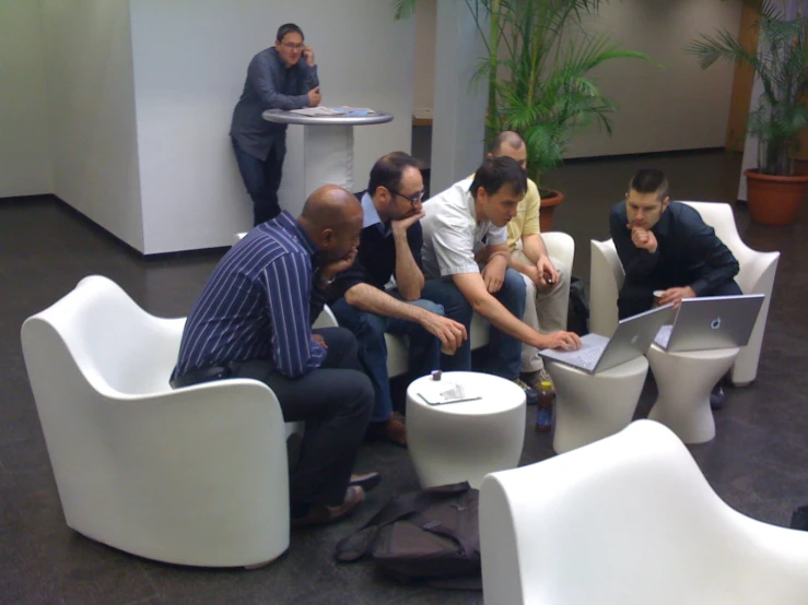 a group of men sitting on white chairs together