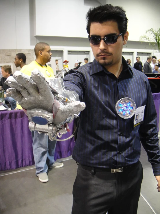 a man holding his hand out to show off the silver robot