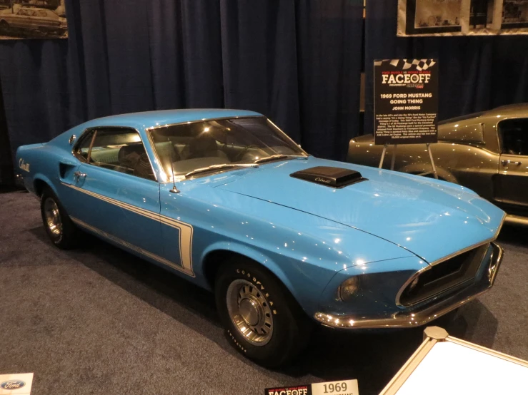 blue muscle car parked on display in the shape of a mustang