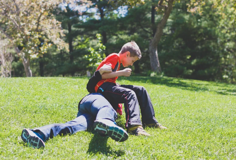 two young men sitting on the ground playing a game