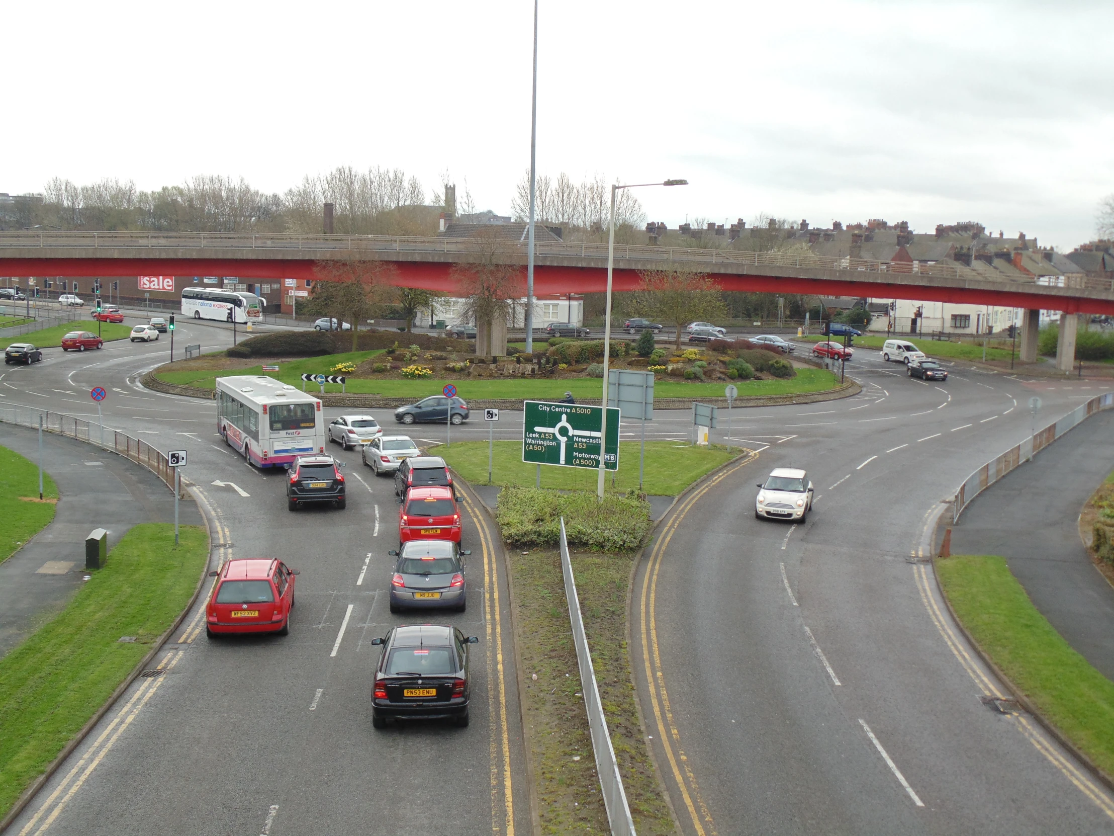 several cars and trucks drive near an elevated highway bridge