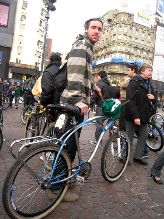 a man with a striped jacket stands beside his bicycle