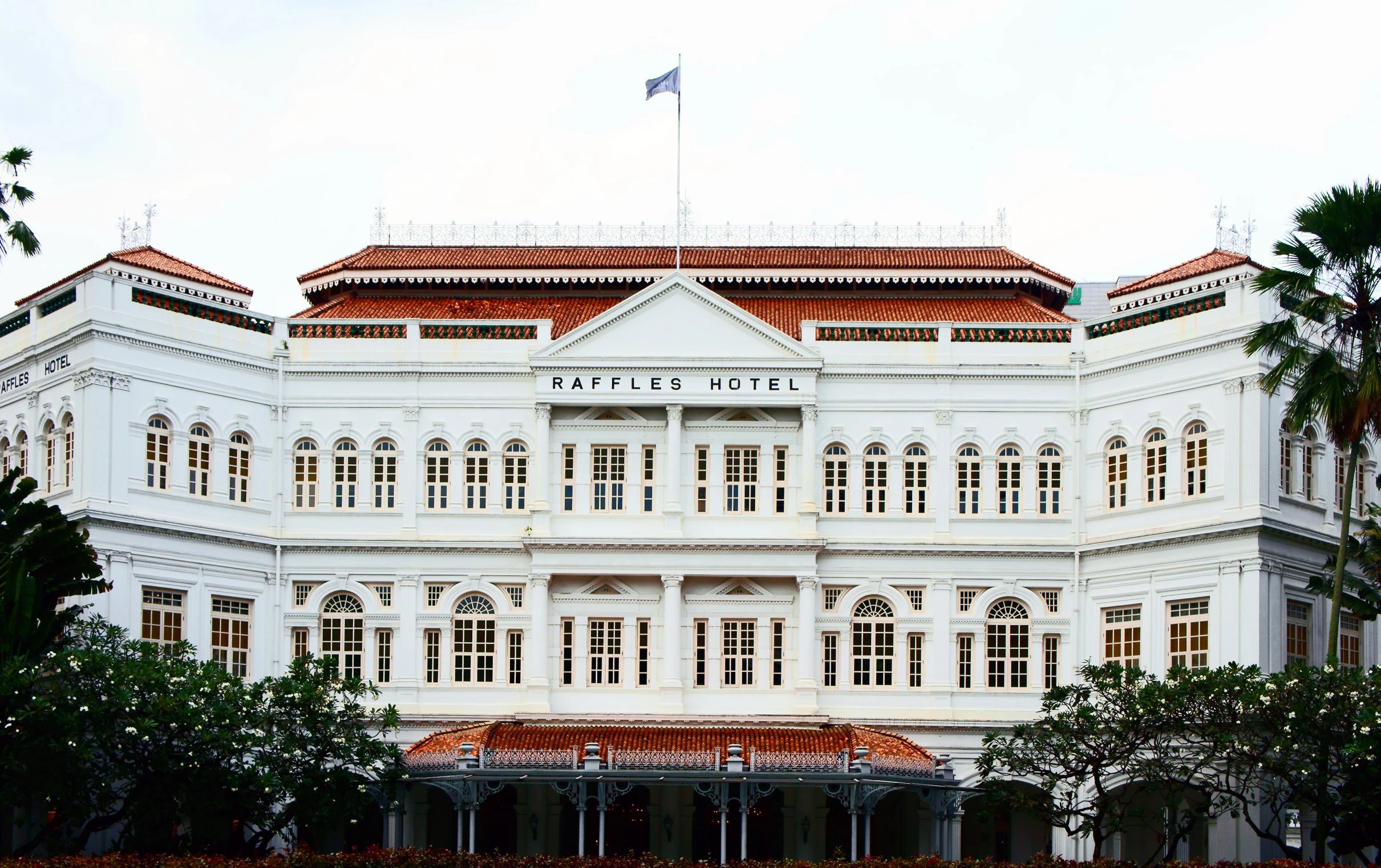 a white building with an orange roof next to trees