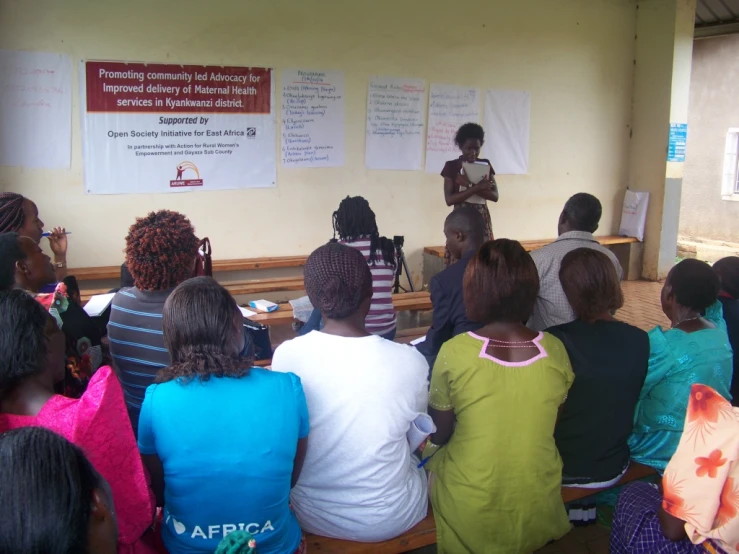 a woman in a black and green shirt talking to a group of children