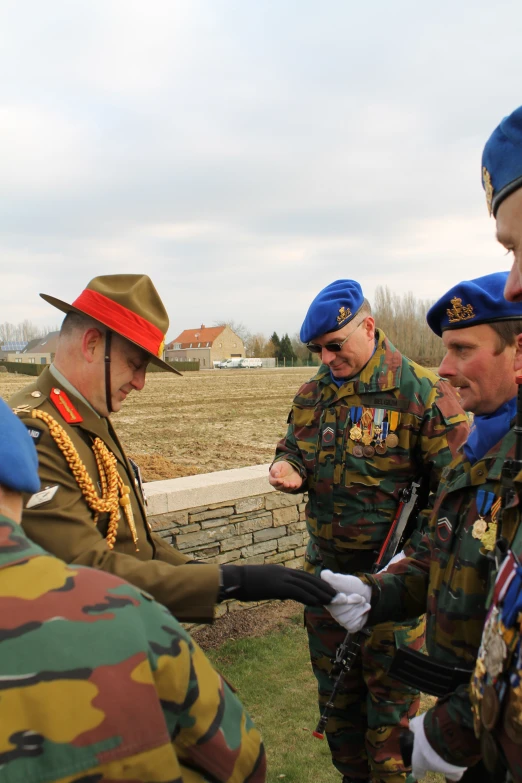 several uniformed men standing in the grass talking