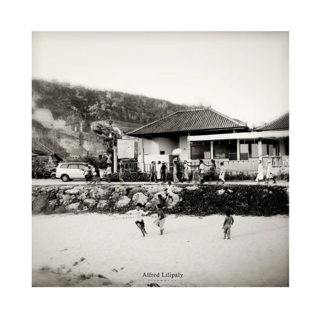 two children are playing in the sand next to a house