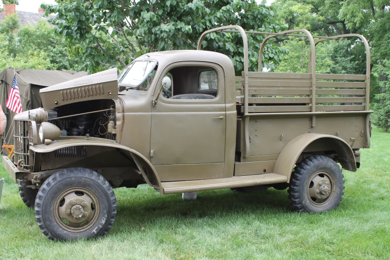 an old green military truck with an american flag on it's back