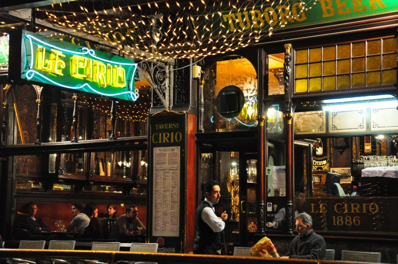 the outside of a bar and grill with neon lights