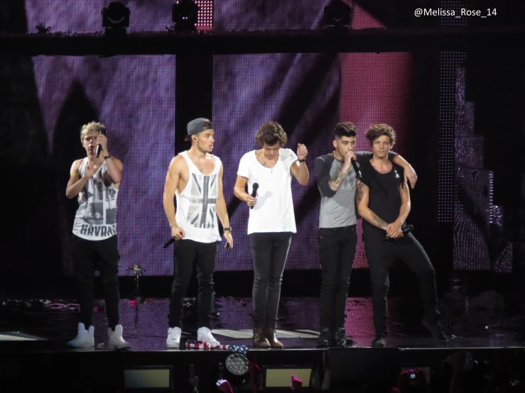 five men on a stage standing together with two holding microphones