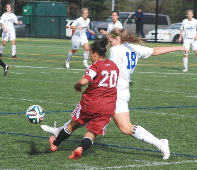 a couple of girls playing soccer against each other on a field