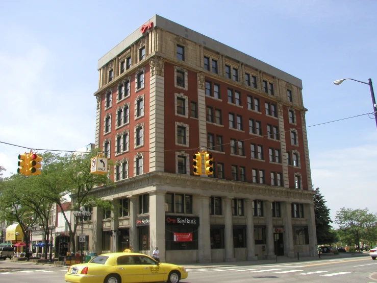 a car sitting on the corner by a tall building