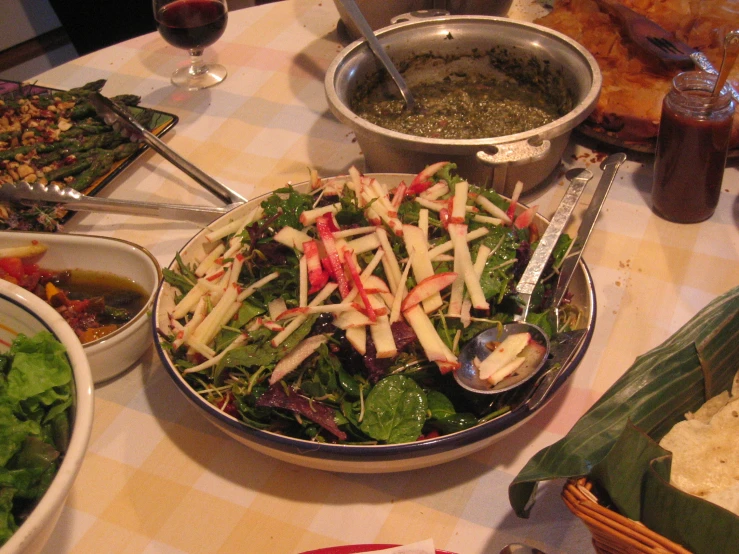 a table topped with bowls of food and two plates of salad