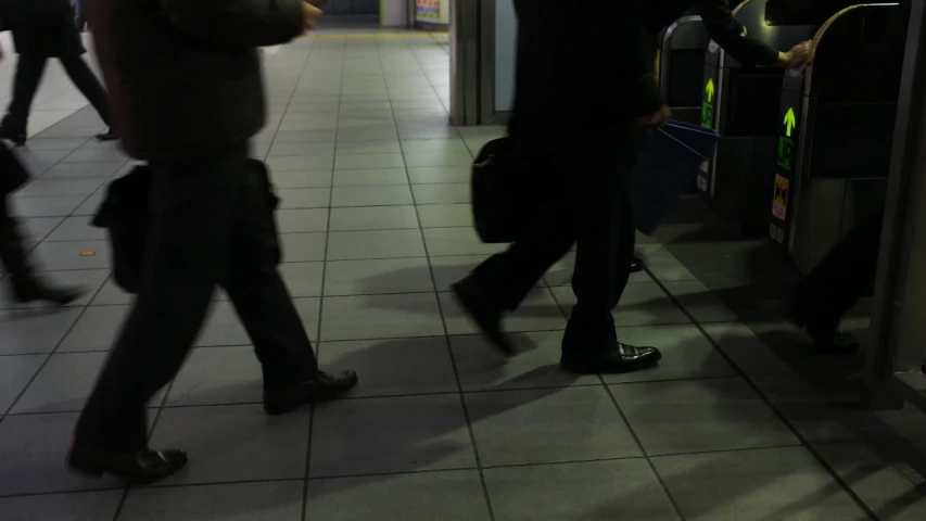 people are standing at the bus station on their cell phones