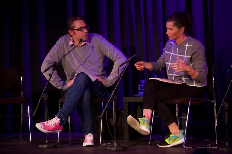 two people sitting on chairs with a microphone behind them