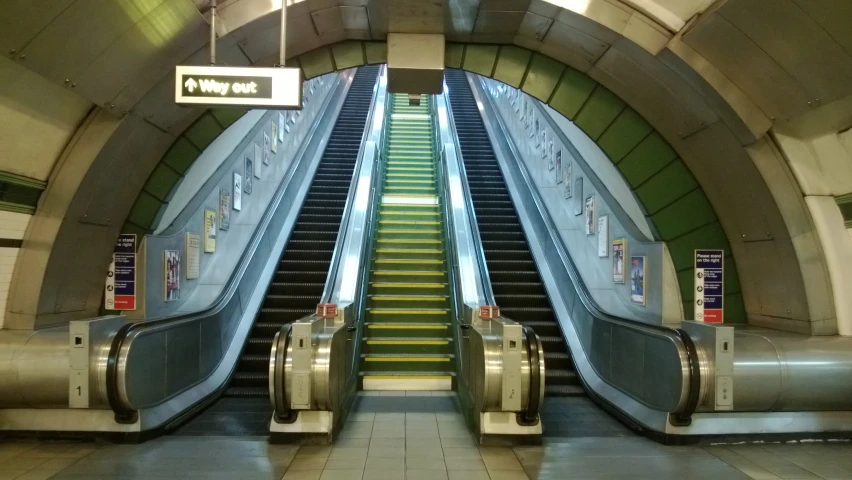an escalator in the middle of an underground building with a staircase leading to it