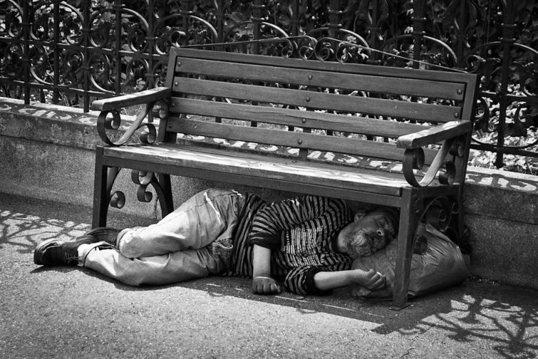a person is sleeping on a bench while leaning against a wall