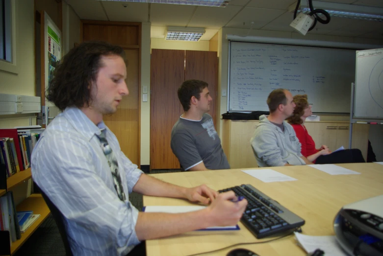 a group of men sitting around a table with a keyboard