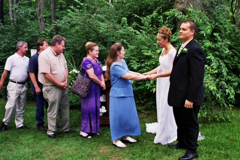 two women shaking hands, surrounded by a group of other people