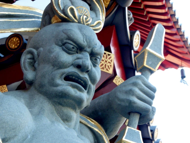 a blue sculpture in front of a red and yellow asian structure